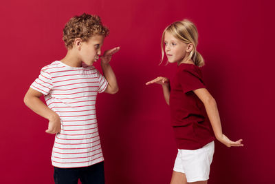 Sibling dancing against maroon background