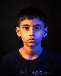 Portrait of young man against black background