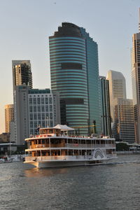 Modern buildings by river against sky in city