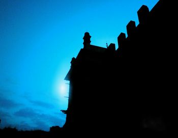 Low angle view of silhouette built structure against blue sky