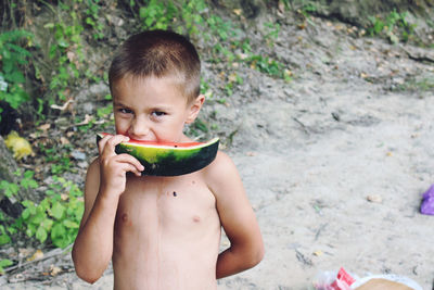 Portrait of shirtless boy eating watermelon