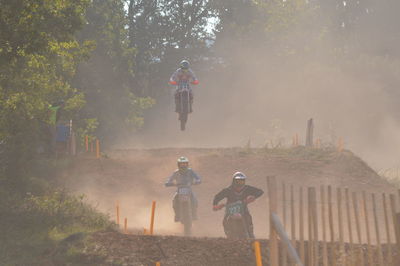 People riding motorcycle on road against trees