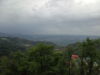 Scenic view of green landscape and sea against sky