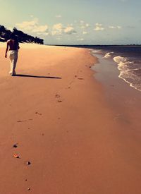 Full length of woman walking on beach against sky