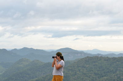 Man photographing with camera standing on mountain