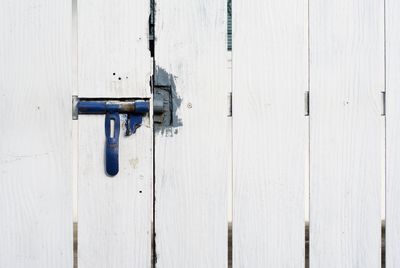 Full frame shot of white wooden gate fence with blue metallic latch