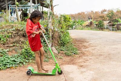 A girl in rural thailand learns to ride a bicycle, scooter, alone.