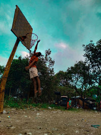 Rear view of man standing by basketball hoop against sky