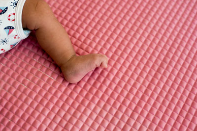 Low section of baby lying down on mat