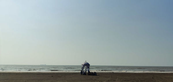 Rear view of men on beach against clear sky