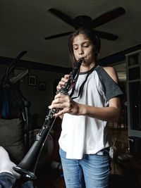 Girl playing musical instrument while standing at home