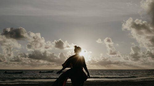 Rear view of woman standing at beach