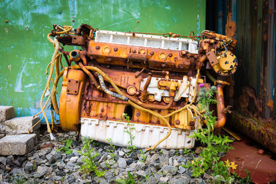 Close-up of old equipment on rocks by wall