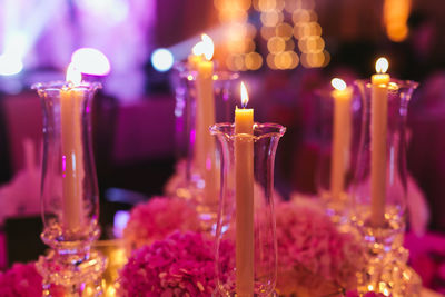 Focus on the candle decoration with pink flowers on the table during a wedding ceremony