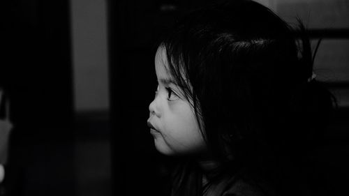 Close-up of cute girl looking away at home