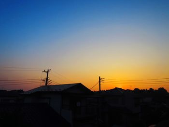 Silhouette houses against sky during sunset