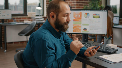 Side view of man using laptop at office