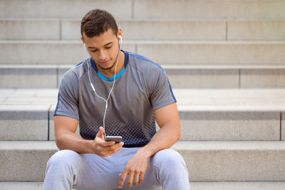 Man using mobile phone while sitting on staircase