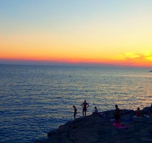 Silhouette people on beach against sky during sunset