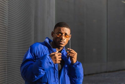 Portrait of young man standing against wall