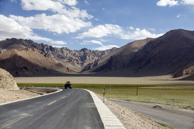 Scenic view of road by snowcapped mountains against sky