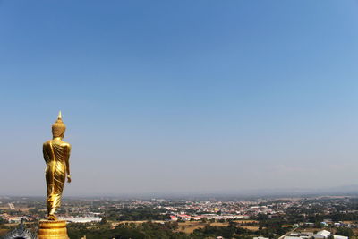 Statue amidst buildings in city against sky