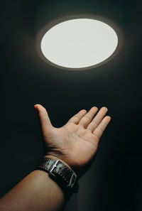 Midsection of person against illuminated light against black background