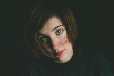 Close-up portrait of a beautiful young woman over black background