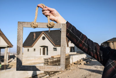 Man holding umbrella against building