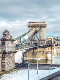 Chain bridge against cloudy sky