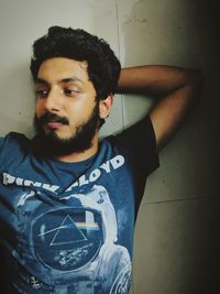 Portrait of young man standing against wall