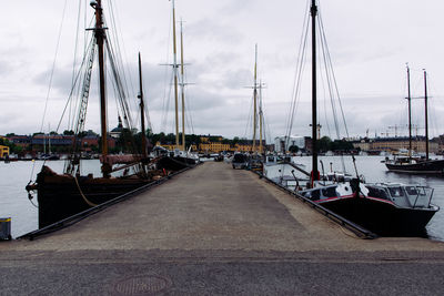 Sailboats moored at harbor against sky