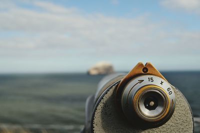 Close-up of coin-operated binoculars on beach against sky