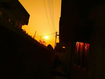 Low angle view of silhouette buildings against orange sky