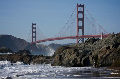 Golden gate bridge of sea against blue sky during sunny day