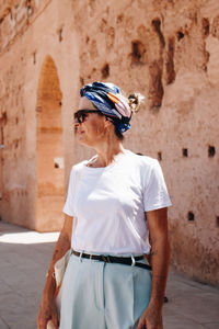 Side view of young woman standing against building