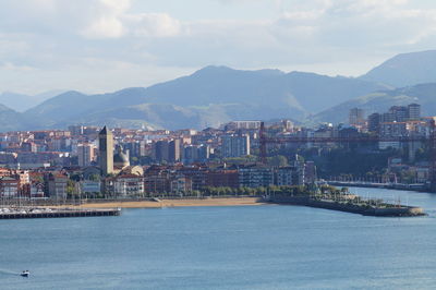 Sea by city buildings against sky