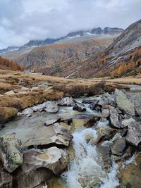 Stream flowing through rocks against sky