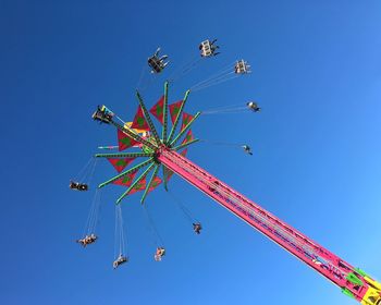 Low angle view of people enjoying chain swing ride against clear sky