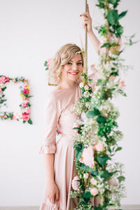 Portrait of smiling young woman standing against wall