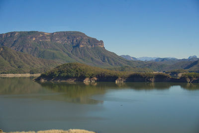 Scenic view of lake and mountains against clear blue sky