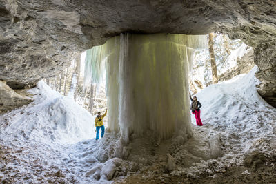 People standing by frozen waterfall