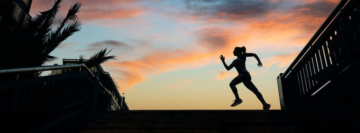 Low angle view of silhouette people on beach against sky during sunset