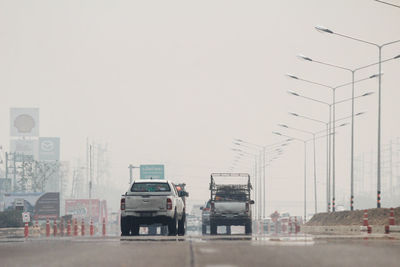 Vehicles on road against sky in city