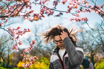 Man with hair in the wind by blooming tree in the park in spring