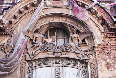 Low angle view of degrading old building with statues