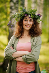 Portrait of young woman standing against plants