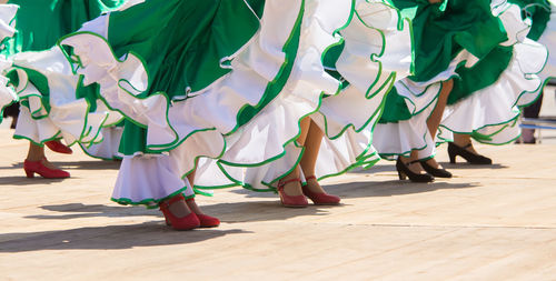 Low section of women dancing on footpath during sunny day