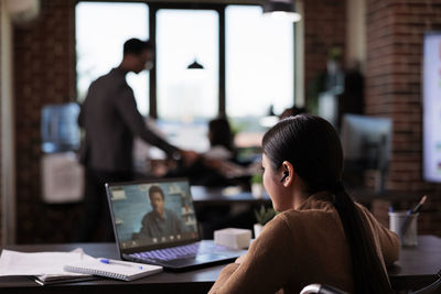 Rear view of man using laptop at office