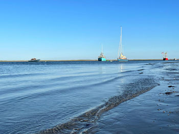 Sailboats on sea against clear blue sky